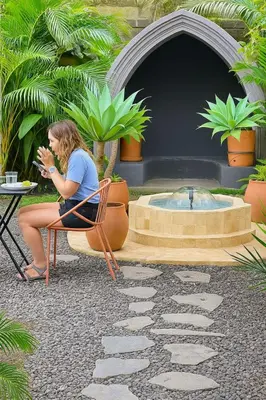 a woman sitting in a chair next to a fountain at awā San José in San José