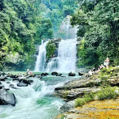 people sitting on rocks in a river with a waterfall at The Scarlet Villas in Ojochal