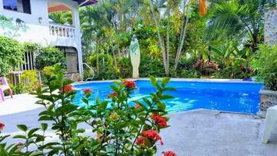 a swimming pool next to a house with flowers at Pacific Jungle Condominium in Playa Hermosa