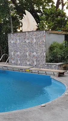 a swimming pool in front of a tile wall at Pacific Jungle Condominium in Playa Hermosa