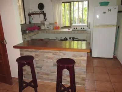 a kitchen with a counter with two stools and a refrigerator at Pacific Jungle Condominium in Playa Hermosa