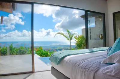a bedroom with a view of the ocean at Golden Pineapple Villas-Adults Only in Uvita