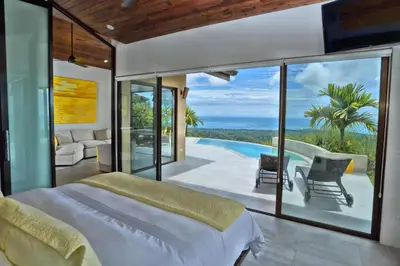 a bedroom with a bed and a view of a pool at Golden Pineapple Villas-Adults Only in Uvita