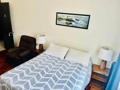 a bedroom with a bed and a chair and a picture at Ester`s Place in Escazu