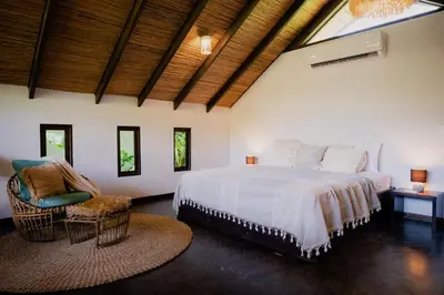 a bedroom with a large bed and a chair at Lua Villas in Santa Teresa Beach