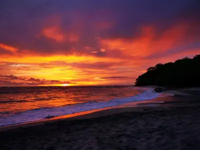 a sunset on a beach with the ocean at Buddha Retreat Hotel in San Juanillo