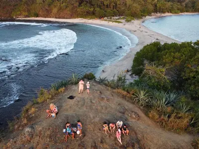 a group of people on a beach near the water at Buddha Retreat Hotel in San Juanillo