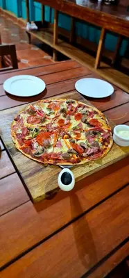 a pizza sitting on top of a wooden table at Buddha Retreat Hotel in San Juanillo