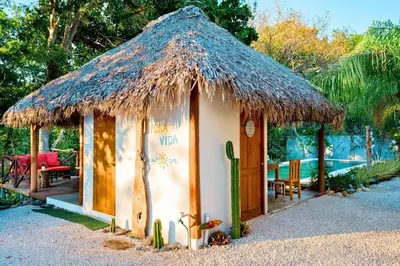 a small hut with a thatched roof and a table and chairs at Antema Lodge Secteur Tamarindo, piscine, yoga, gym, jungle et paix in Tamarindo