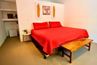 a bedroom with a red bed with a red bedspread at Antema Lodge Secteur Tamarindo, piscine, yoga, gym, jungle et paix in Tamarindo