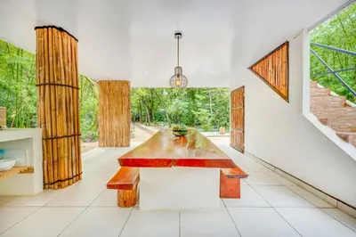 a dining room with a table and a large window at Antema Lodge Secteur Tamarindo, piscine, yoga, gym, jungle et paix in Tamarindo