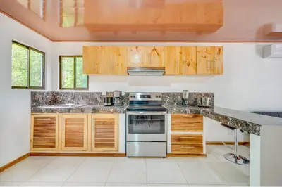 a kitchen with wooden cabinets and a stove at Antema Lodge Secteur Tamarindo, piscine, yoga, gym, jungle et paix in Tamarindo