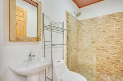 a bathroom with a sink and a toilet and a mirror at Antema Lodge Secteur Tamarindo, piscine, yoga, gym, jungle et paix in Tamarindo
