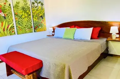 a bedroom with a bed with a red stool at Antema Lodge Secteur Tamarindo, piscine, yoga, gym, jungle et paix in Tamarindo