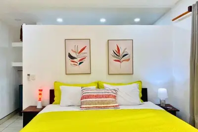 a bedroom with a yellow bed with two pictures on the wall at Antema Lodge Secteur Tamarindo, piscine, yoga, gym, jungle et paix in Tamarindo