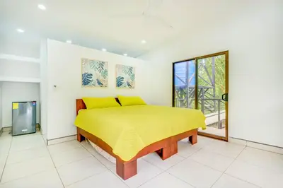 a bedroom with a yellow bed and a window at Antema Lodge Secteur Tamarindo, piscine, yoga, gym, jungle et paix in Tamarindo