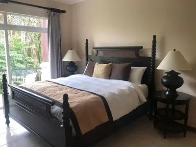 a bedroom with a bed with two lamps and a window at Palm Coast Luxury Rentals in Esterillos Este