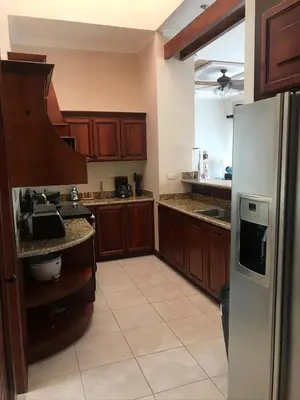 a kitchen with wooden cabinets and a stainless steel refrigerator at Palm Coast Luxury Rentals in Esterillos Este
