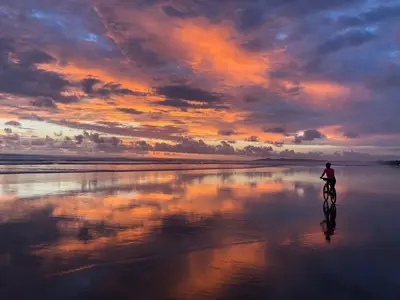 a person riding a bike on the beach at sunset at Palm Coast Luxury Rentals in Esterillos Este