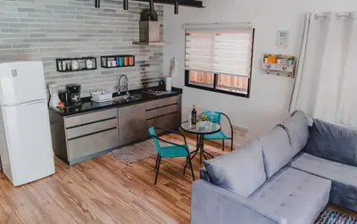 a living room with a couch and a table and a kitchen at Peace Lofts and Apartments in Santa Teresa Beach