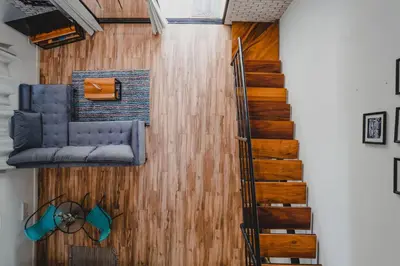 a living room with a wooden wall and a staircase at Peace Lofts and Apartments in Santa Teresa Beach