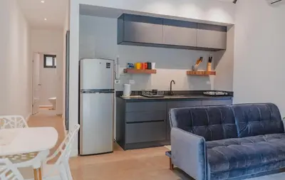 a kitchen with a refrigerator and a table and a couch at Peace Lofts and Apartments in Santa Teresa Beach