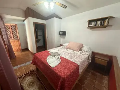 a small bedroom with a bed with a red blanket at Hotel Don Quichotte in Tortuguero