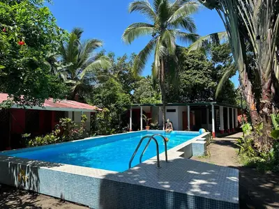 a swimming pool in front of a villa at Hotel Don Quichotte in Tortuguero