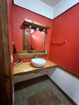 a bathroom with a white sink and a red wall at Hotel Don Quichotte in Tortuguero