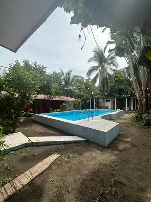 a large swimming pool in front of a house at Hotel Don Quichotte in Tortuguero