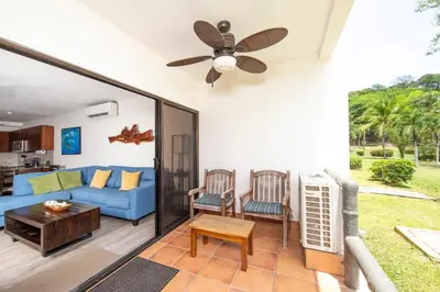 a living room with a blue couch and a ceiling fan at Newly Remodeled Beachfront Condo, Ground-Floor Terrace & Direct Access to Playa Flamingo in Playa Flamingo