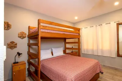 a bedroom with a bunk bed with a red bedspread at Newly Remodeled Beachfront Condo, Ground-Floor Terrace & Direct Access to Playa Flamingo in Playa Flamingo