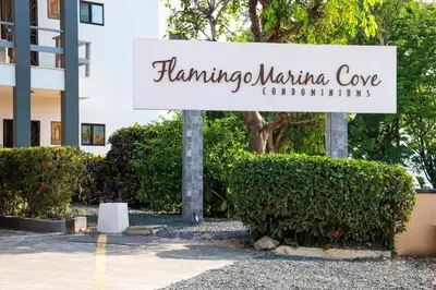 a sign in front of a building with bushes at Newly Remodeled Beachfront Condo, Ground-Floor Terrace & Direct Access to Playa Flamingo in Playa Flamingo