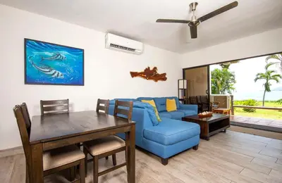 a living room with a blue couch and a table at Newly Remodeled Beachfront Condo, Ground-Floor Terrace & Direct Access to Playa Flamingo in Playa Flamingo