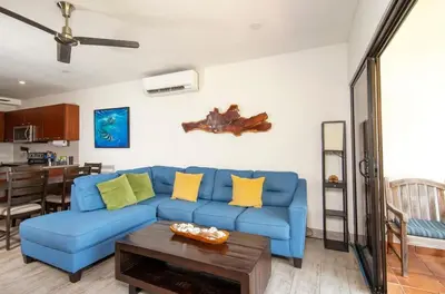 a living room with a blue couch and a table at Newly Remodeled Beachfront Condo, Ground-Floor Terrace & Direct Access to Playa Flamingo in Playa Flamingo