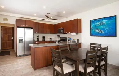 a kitchen with a table and a kitchen with a refrigerator at Newly Remodeled Beachfront Condo, Ground-Floor Terrace & Direct Access to Playa Flamingo in Playa Flamingo