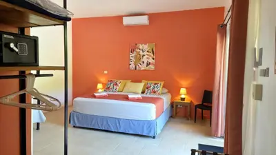 a bedroom with a bed with an orange wall at Tee-K Lodge Tamarindo in Tamarindo