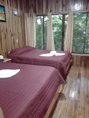 two beds sitting in a room with windows at The Green Tree Lodge in Monteverde Costa Rica