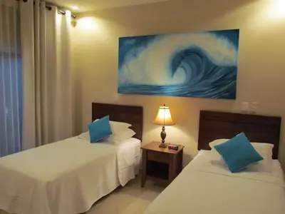 two beds in a room with a painting on the wall at Tamarindo Condo 206 Matapalo in Tamarindo