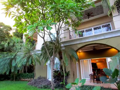 a house with a palm tree in front of it at Tamarindo Condo 206 Matapalo in Tamarindo
