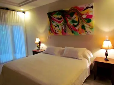 a bedroom with a white bed and a painting on the wall at Tamarindo Condo 206 Matapalo in Tamarindo
