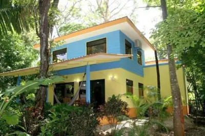 a blue and yellow house in the forest at Nosara Paradise Rentals in Nosara