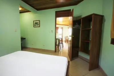 a bedroom with a white bed and a green wall at Nosara Paradise Rentals in Nosara