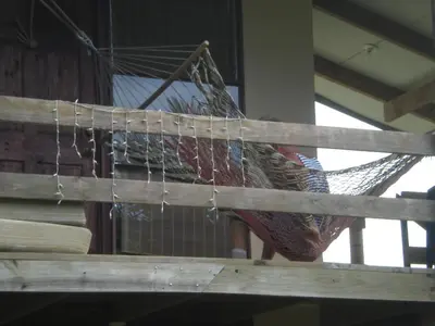 a hammock hanging from a wooden railing in a room at Lodge El Barco in Esterillos
