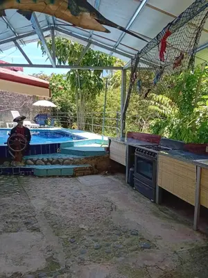 a backyard with a pool and an outdoor kitchen with a stove at Lodge El Barco in Esterillos