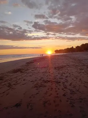 a sunset on a beach with the sun setting at Lodge El Barco in Esterillos