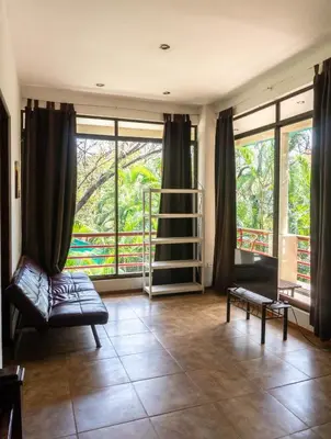 a living room with a couch and large windows at Chicama : Burnt Toast Surfcamp in Nosara
