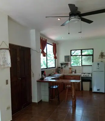 a kitchen with a table and a ceiling fan at Chicama : Burnt Toast Surfcamp in Nosara