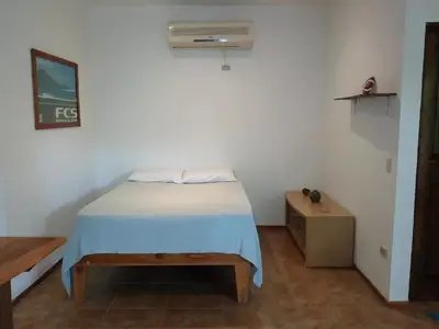 a small bedroom with a bed and a air conditioner at Chicama : Burnt Toast Surfcamp in Nosara