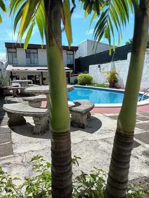 a group of picnic tables and palm trees next to a pool at Hotel Casa Tago in Alajuela City